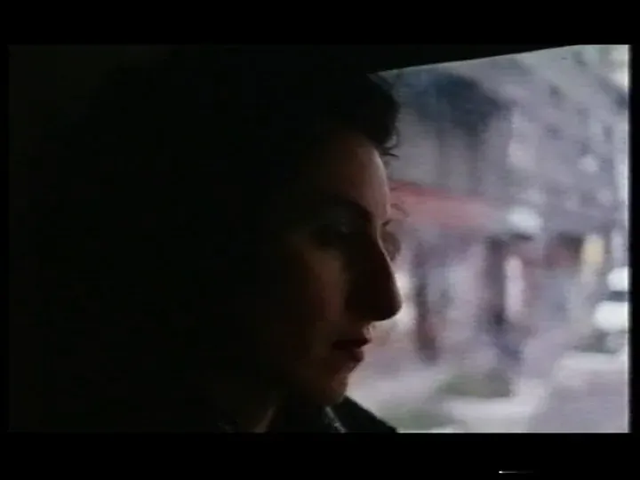 A woman in profile, in shadow against a bright window, a street passing blurred behind her